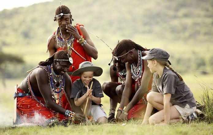 Travellers learning beadwork from Maasai hosts on a cultural visit
